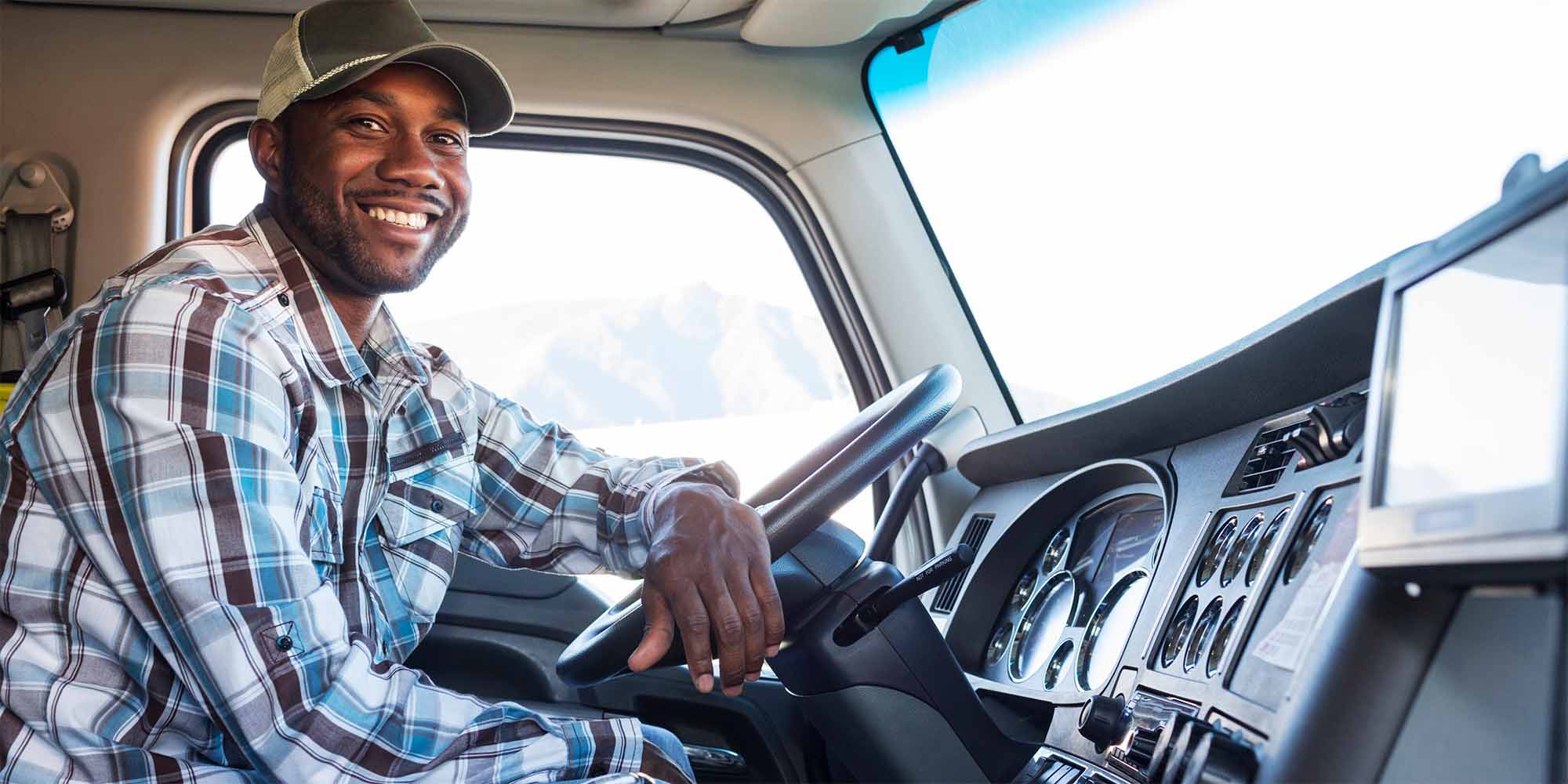 Black truck driver smiling in the cab of his semi truck